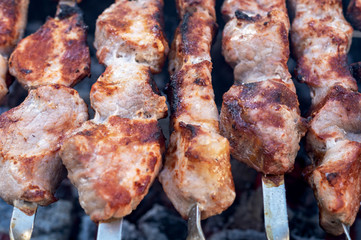 Shashlik or Shish kebab popular in Eastern Europe. BBQ fresh meat pork slices. Grill on charcoal and flame, picnic