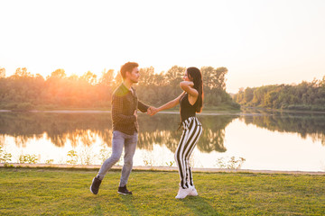 Romantic, social dance, people concept - young couple dancing bachata near the lake in sunny day