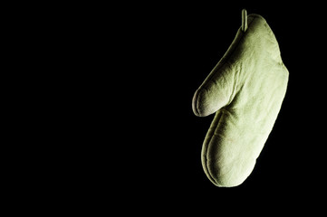 Green glove to protect hands and baking on a black background, isolate