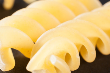 Spiral pasta from durum wheat on a dark background, close-up. Macro shooting.