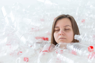 Environmental Protection, people and recyclable plastic concept - exhausted woman concerned with environment disaster sitting in a pile plastic bottles