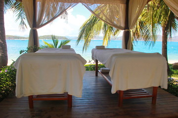 Spa massage room at beachside in bungalow, massage tables with towels. Beauty care concept. Spa beds ready to massage at outdoors tropical island resort.