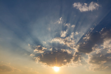Naklejka na ściany i meble Besutiful ray of sunlight breaking through clouds at sunset.