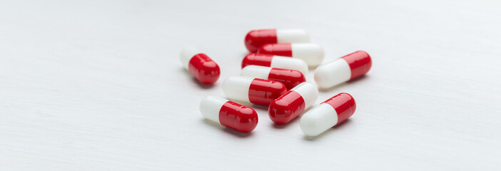 Red and white pills on a white table background with copy space. Concept of medication of vitamins...
