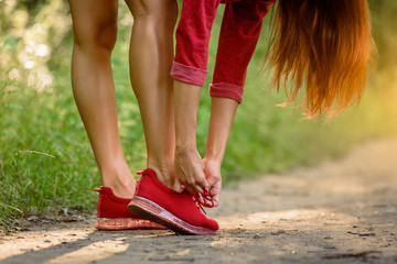 Female runner prepare for training and tying shoe laces in park