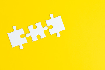 3 jigsaw puzzle on solid yellow background using as 3 important thing combine or working together...