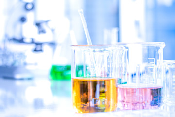Different laboratory glassware with color liquid and with reflection. Tube, flask and beaker and microsope background