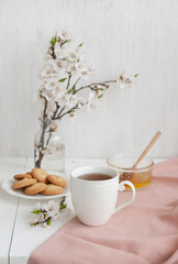 A tasty break: a cup of tea, a bowl of honey and a plate of cookies.