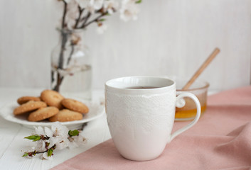 Obraz na płótnie Canvas A tasty break: a cup of tea, a bowl of honey and a plate of cookies.
