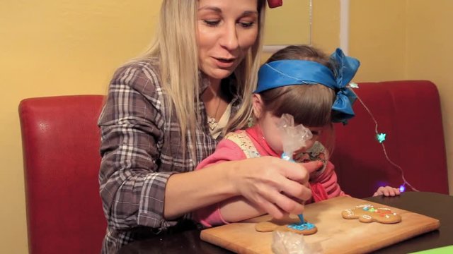 mom and little daughter paint Christmas gingerbread together