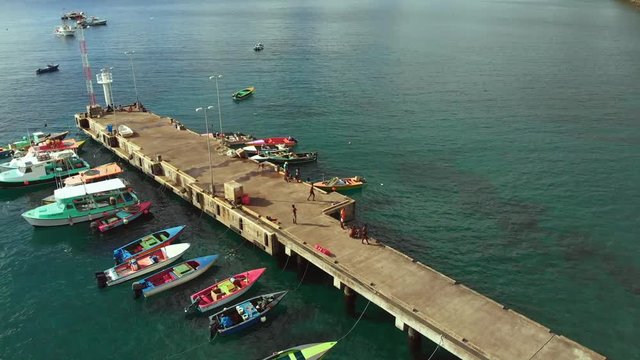 Epic helix aerial of drone footage over a Gouyave fish market on the spice island of Grenada with boats anchored at the jetty