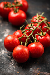 Cherry tomatoes on vine on dark rusty background. Vertical orientation