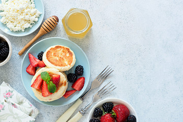 Syrniki, cottage cheese pancakes with berries and honey. Table top view, copy space. Tasty healthy breakfast, rich in Calcium and Protein