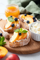 Appetizer Bruschetta With Ricotta Cheese, Fruits And Honey On Wooden Serving Board. Closeup View, Selective Focus