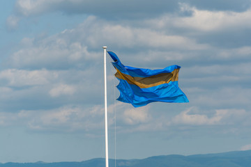 Waving Szekler flag against a cloudy sky at local horse race in Moacsa, Covasna.