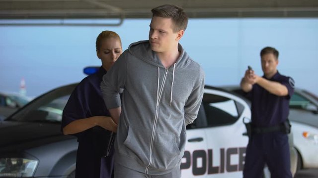 Cops arresting criminal, male officer aiming gun, police woman wearing handcuffs