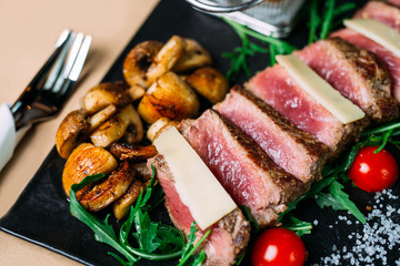 Sliced grilled beef barbecue steak and salad with tomatoes and arugula