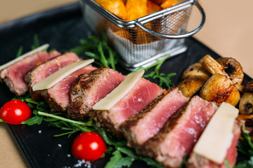 Sliced grilled beef barbecue steak and salad with tomatoes and arugula