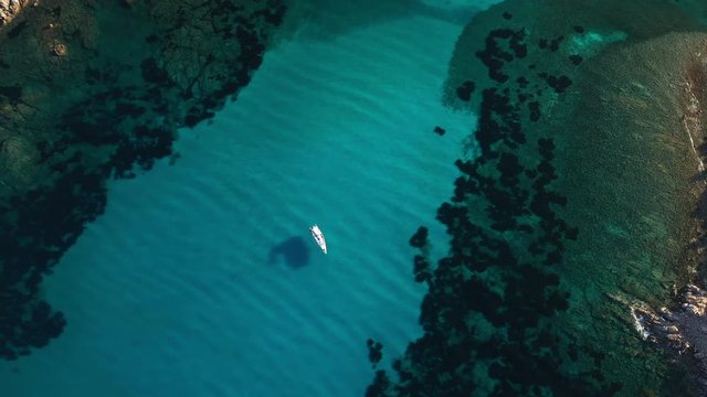 View from above, stunning aerial view of a sailing boat floating on a beautiful turquoise clear sea. Maddalena Archipelago National Park, Sardinia, Italy.