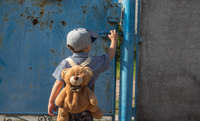 a back of the boy in a cap shirt and with a backpack near the gate