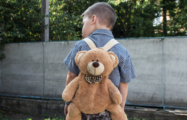 a back of the boy in a shirt and with a backpack
