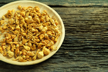Dried cordyceps militaris in wooden dish on old wooden floors