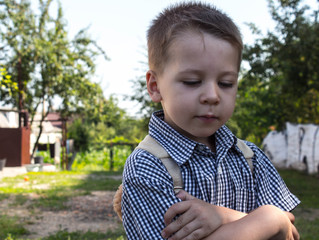 the boy in a shirt and with a backpack look down
