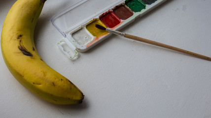 a banana watercolor paint and brush on white background
