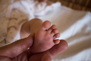 the newborn baby leg in father's hands