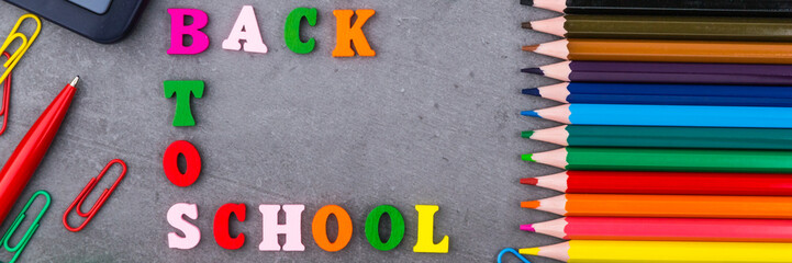 Fototapeta premium The layout of school supplies on a dark gray background. The view from the top. Flat lay. Back to school.