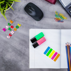 The layout of school supplies on a dark gray background. Top view, the sun's rays from the side....