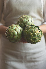 Obraz premium The girl is holding an artichoke in her hands. A concept of proper and dietary nutrition, Dotex