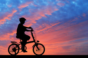 Obraz premium Silhouette man and bike relaxing on blurry sunrise sky background.