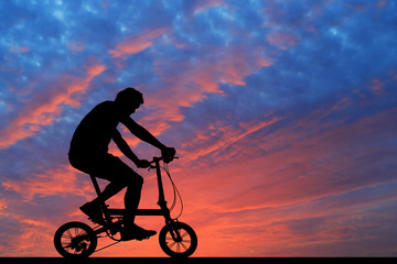 Silhouette man  and bike relaxing on blurry sunrise  sky   background.