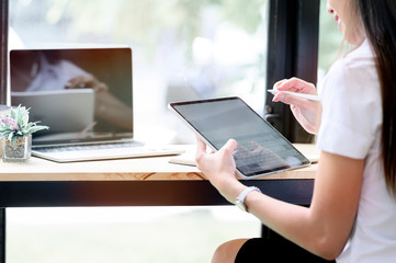 Young female student using tablet while sitting at table in co workspace.