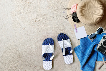 Fototapeta na wymiar Beach background with sandals, straw hat, towel and camera, top view.
