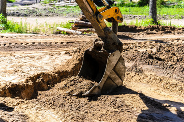 the concept of the tractor, the tractor digs and buries a trench for laying water on a forest plot for the construction of the house. help workers.