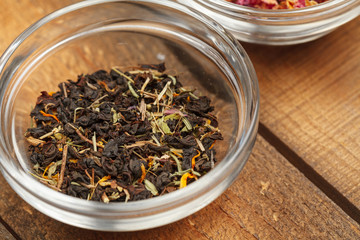Aromatic dry tea in bowls on wooden background