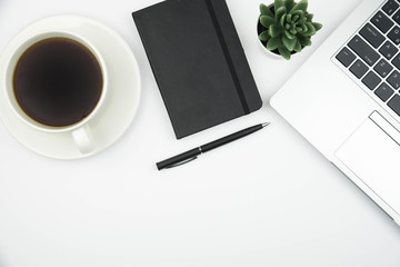 Modern office desk workspace with coffee cup, notebook, laptop and succulent with copy space on white background. Top view. Flat lay. Education, freelance and business concept