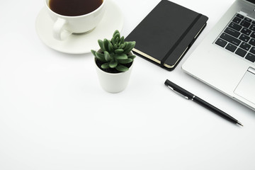 Modern office desk workspace with coffee cup, notebook, laptop and succulent with copy space on white background. Top view. Flat lay. Education, freelance and business concept