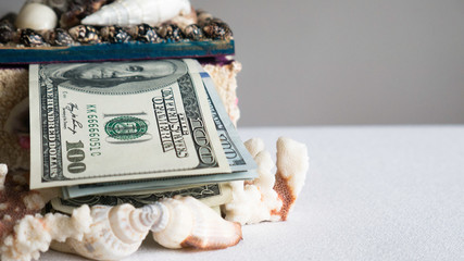 Stack of one hundred dollar bills in a box of seashells