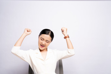 Happy woman make winning gesture sitting isolated over white background