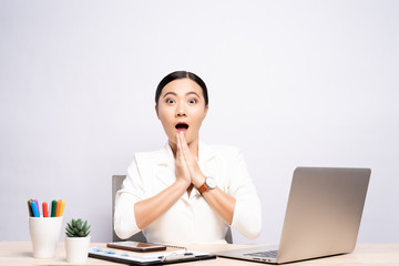 Portrait of a excited woman sitting at office isolated over background