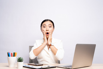 Portrait of a excited woman sitting at office isolated over background