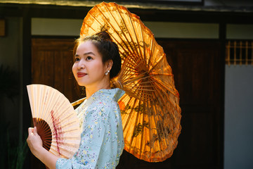 Lifestyle series: Asian woman holding paper umbrella and paper fan in ryokan