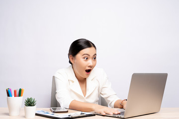 Portrait of a excited woman sitting at office isolated over background
