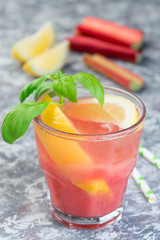 Obraz premium Refreshing lemonade with rhubarb, lemon, sparkling water and basil in a glass, vertical
