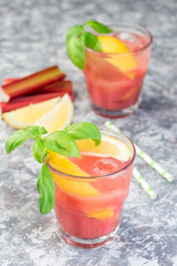 Refreshing lemonade with rhubarb, lemon, sparkling water and basil in  glass, vertical