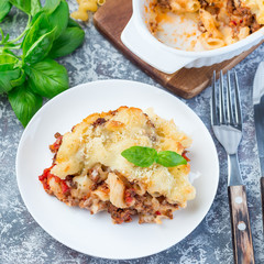 Macaroni casserole with ground beef, cheese and tomato on plate, vertical, top view, square format
