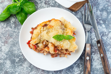 Macaroni casserole with ground beef, cheese and tomato on white plate, horizontal,  top view